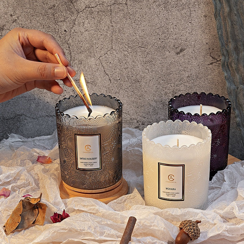 Candle being lit with a match, surrounded by three other candles on a textured surface.