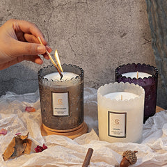 Candle being lit with a match, surrounded by three other candles on a textured surface.