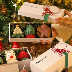 Handmade Christmas ornaments in a box with a decorative ribbon against a festive background.