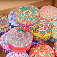 Colorful round containers with intricate patterns stacked on a brown surface