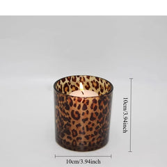 Candle in a leopard print glass holder with dimensions indicated on a gray background