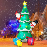 Inflatable Christmas tree decoration with Santa and snowman in front of a house at night.
