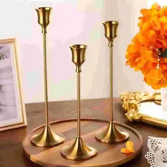 Three gold candle holders on a wooden tray with a decorative background