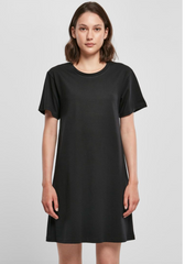 A woman modeling a plain black short-sleeve crewneck dress against a light gray studio background.