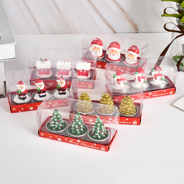 Set of Christmas-themed candles in clear and red packaging on a white surface.