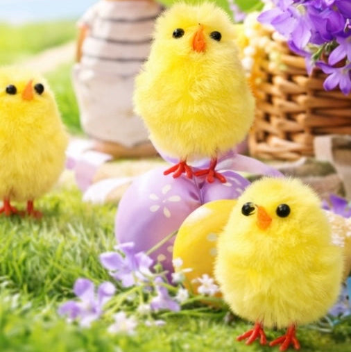 Yellow fluffy chicks with Easter eggs and a bunny in a garden setting