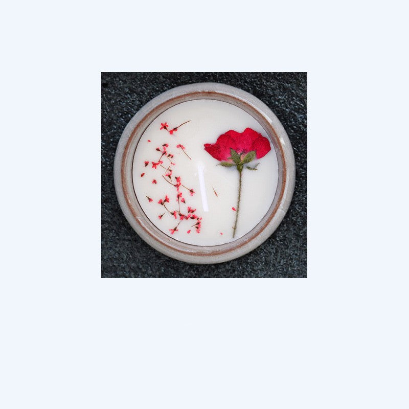 Round ceramic plate with a red rose and petals on a textured surface