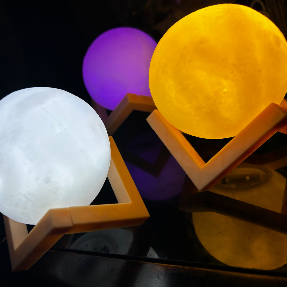 Three moon-shaped lamps in white, purple, and yellow on a dark background