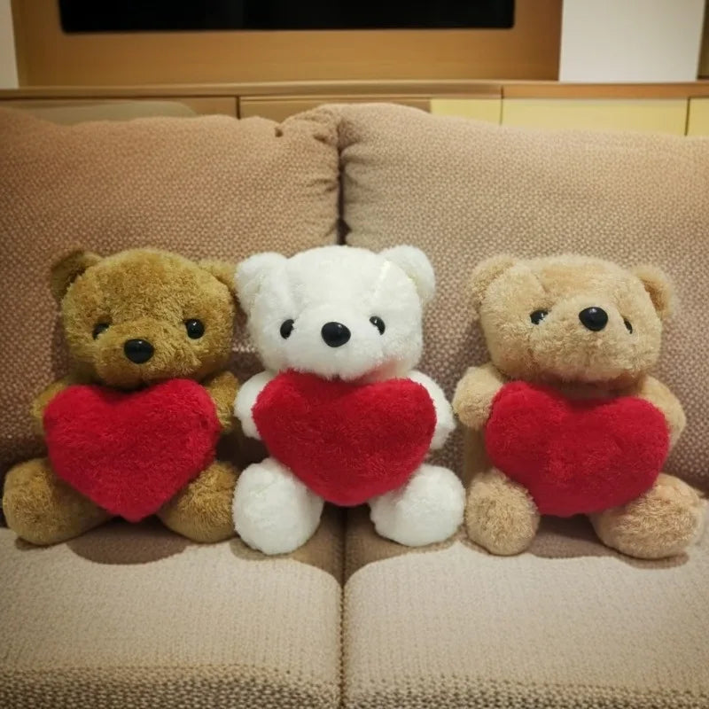 Three teddy bears with red hearts on a beige couch.