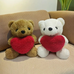 Two teddy bears, one brown and one white, holding red hearts on a beige couch.