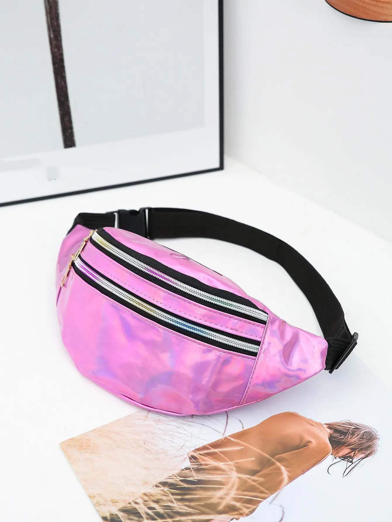 Pink tie-dye fanny pack with a black strap on a white surface.