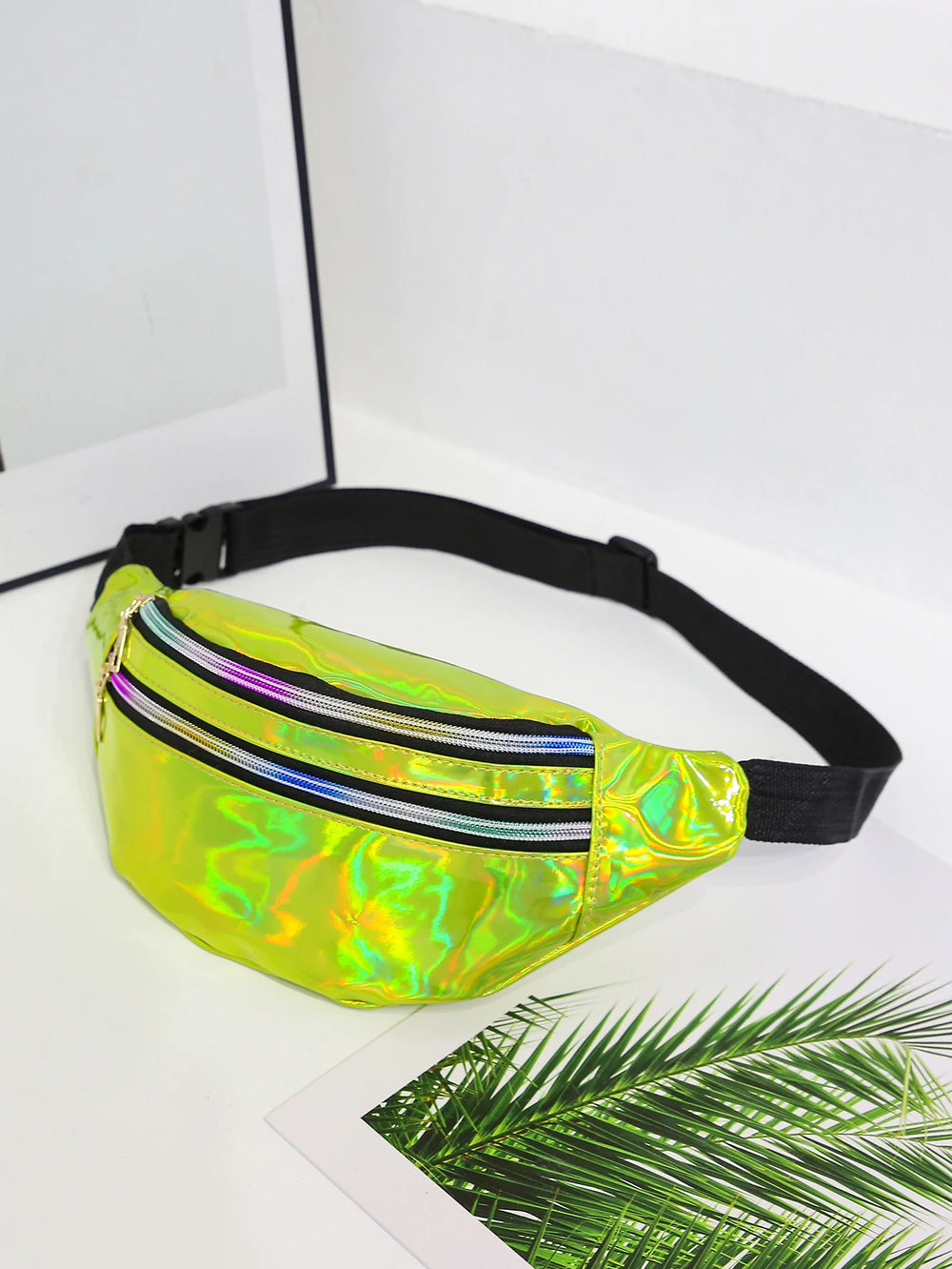 Holographic fanny pack on a white surface with a leafy green plant in the corner