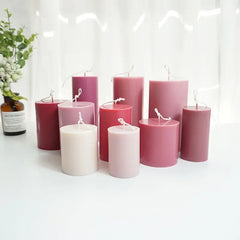 Set of pink and white candles on a white surface with a blurred background