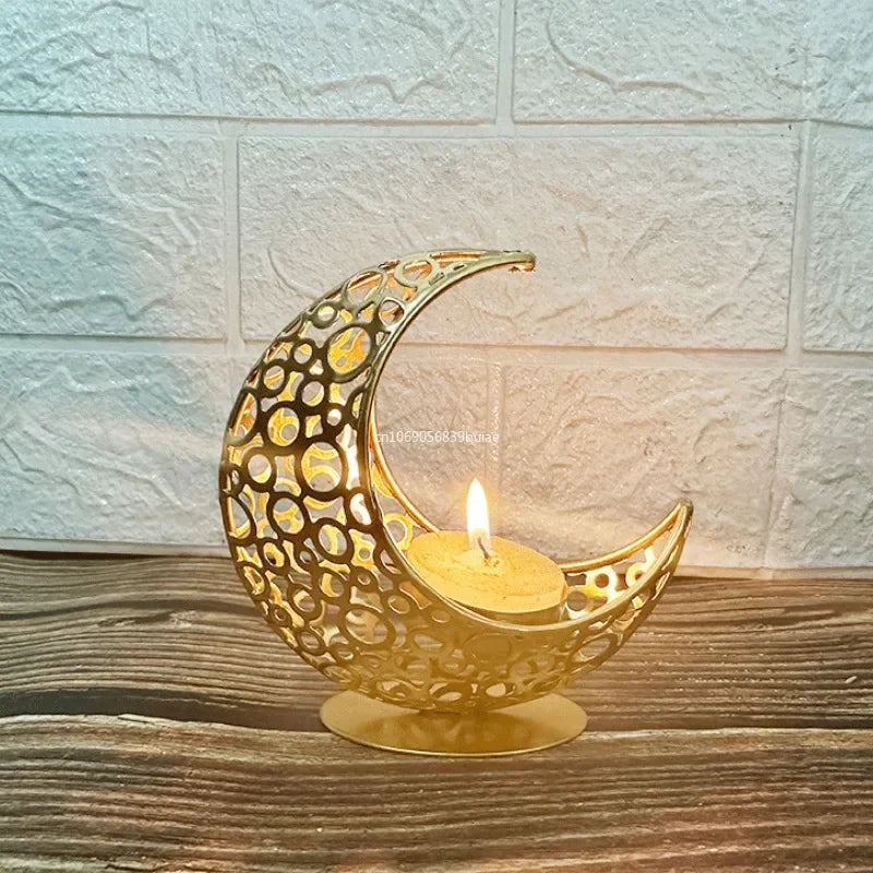 Decorative gold crescent moon candle holder with a lit candle on a wooden surface.