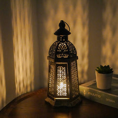 Decorative lantern with intricate patterns on a wooden surface, casting a warm glow.