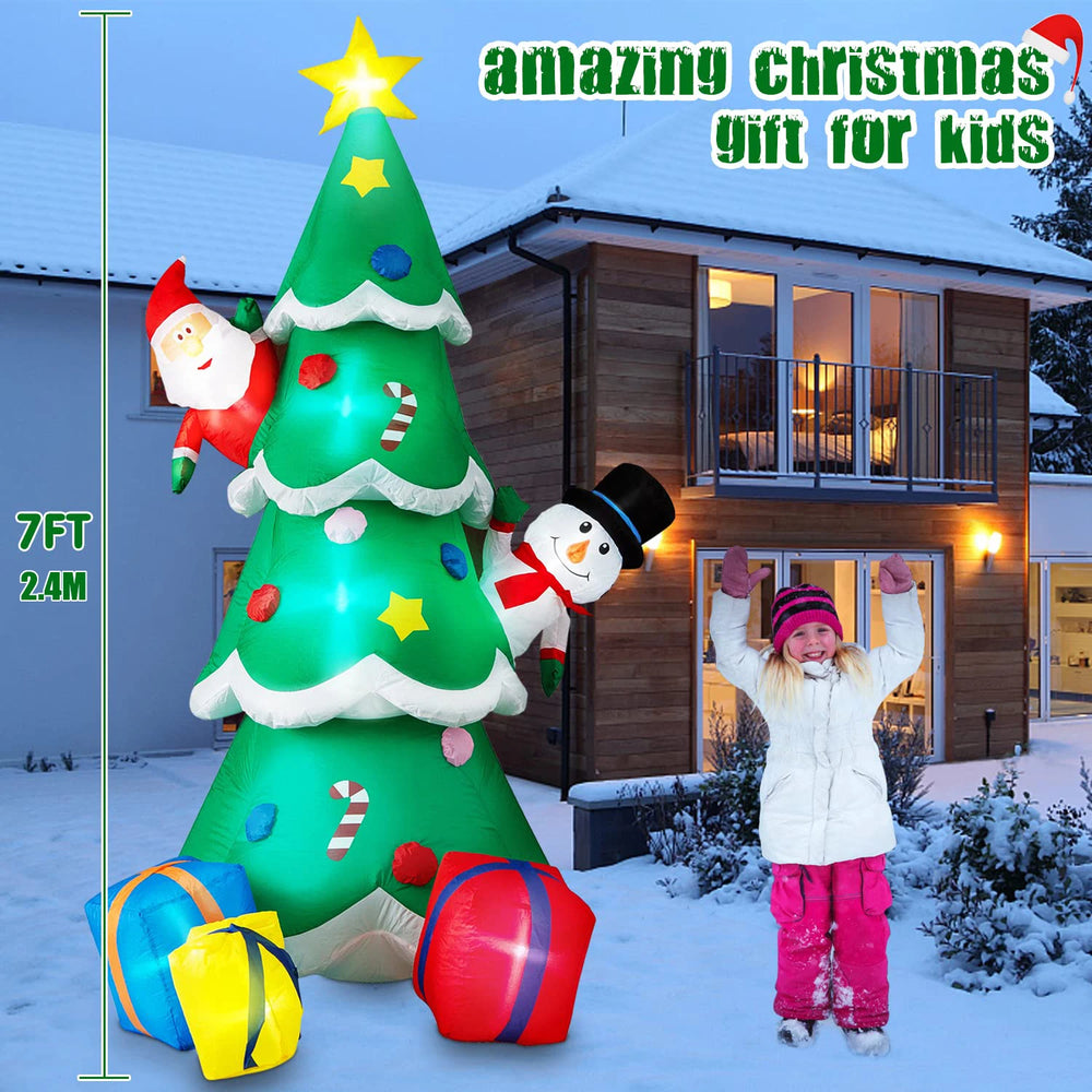 Inflatable Christmas tree with decorations and a child in front, set against a snowy house exterior.