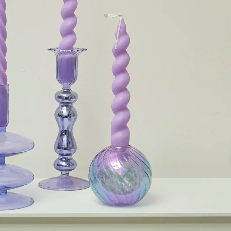 Purple twisted candle on a decorative stand against a white background