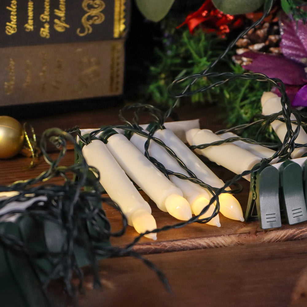String lights with candles on a wooden surface, with a book and decorative items in the background.