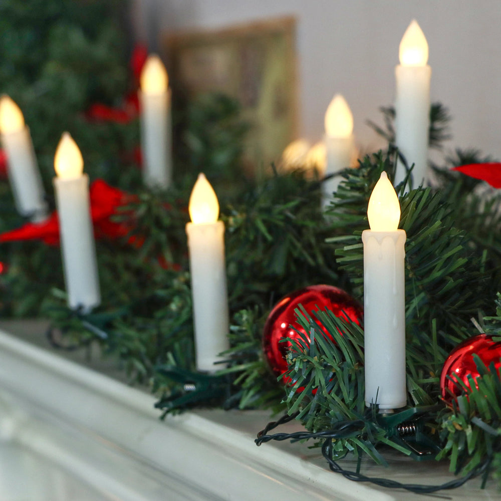 Decorative Christmas garland with candles and red ornaments on a mantelpiece.
