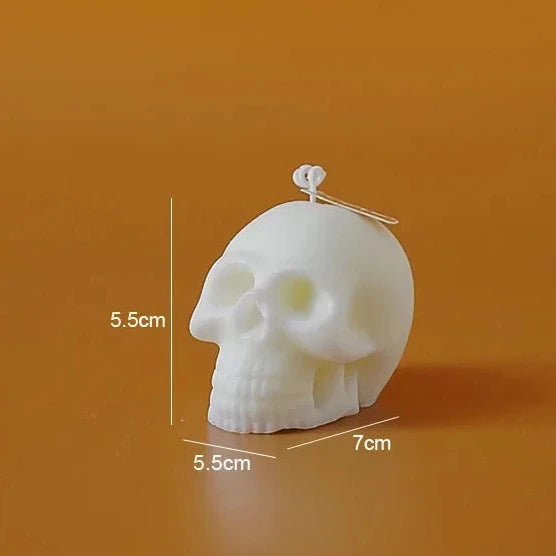 A white skull-shaped candle on a warm orange-brown background, with measurement labels showing 5.5 cm height, 5.