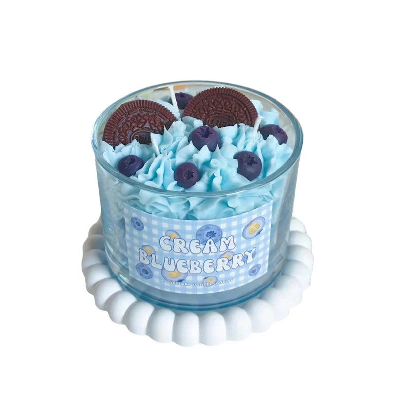 Blueberry flavored candle with cookies on top on a white background