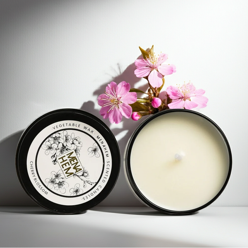Candle in a black container with cherry blossoms on a white background