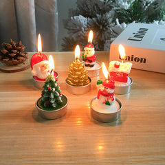 Set of Christmas-themed candles on a wooden surface with a blurred background