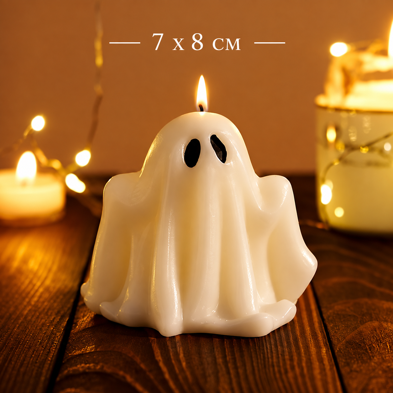 A ghost-shaped white candle with black eyes sits on a wooden surface, surrounded by warm lit candles and string lights. White text at the top reads '7 x 8 CM'.