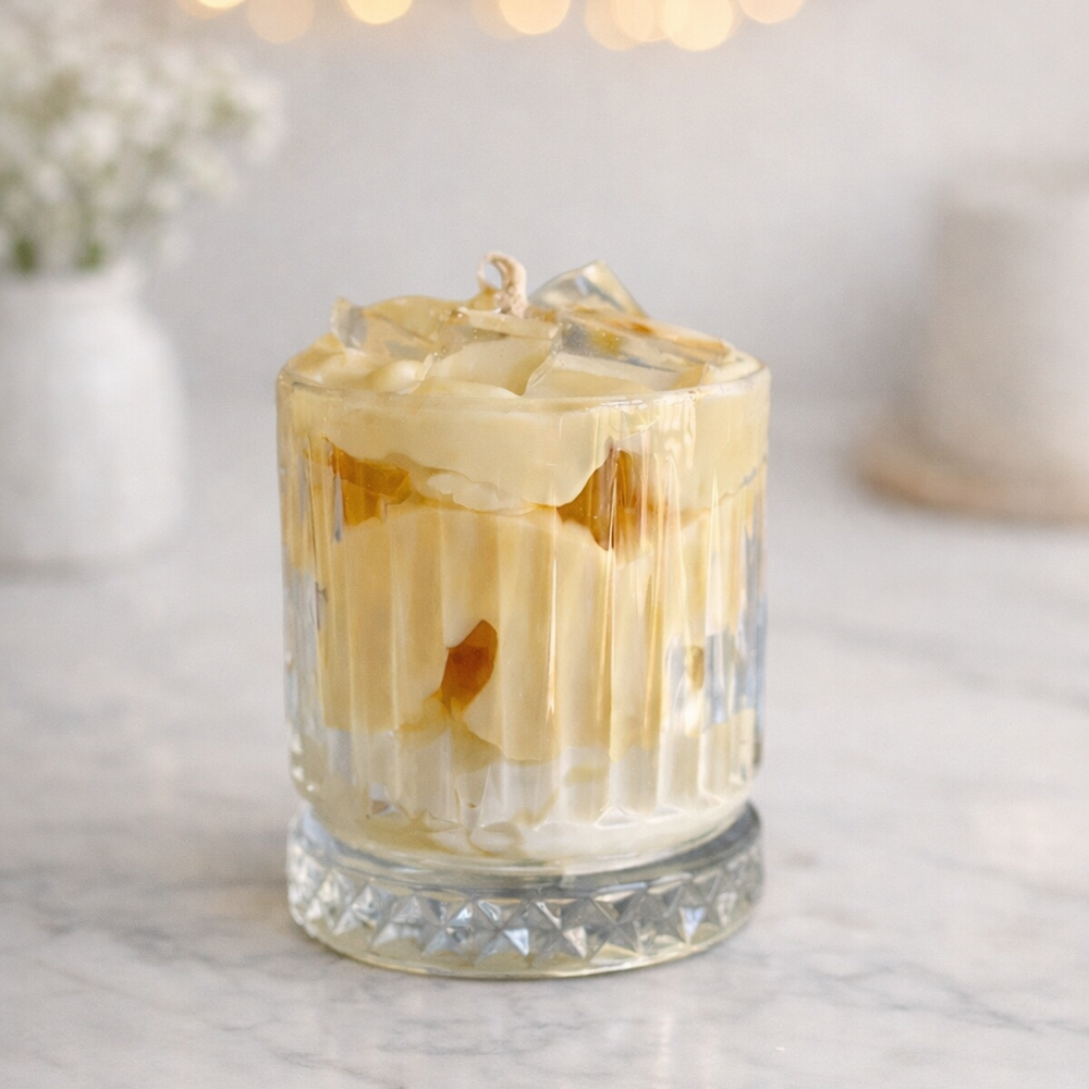 Glass of iced coffee with ice cubes on a marble surface with blurred lights in the background
