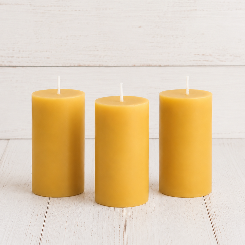 Three yellow candles on a white wooden surface